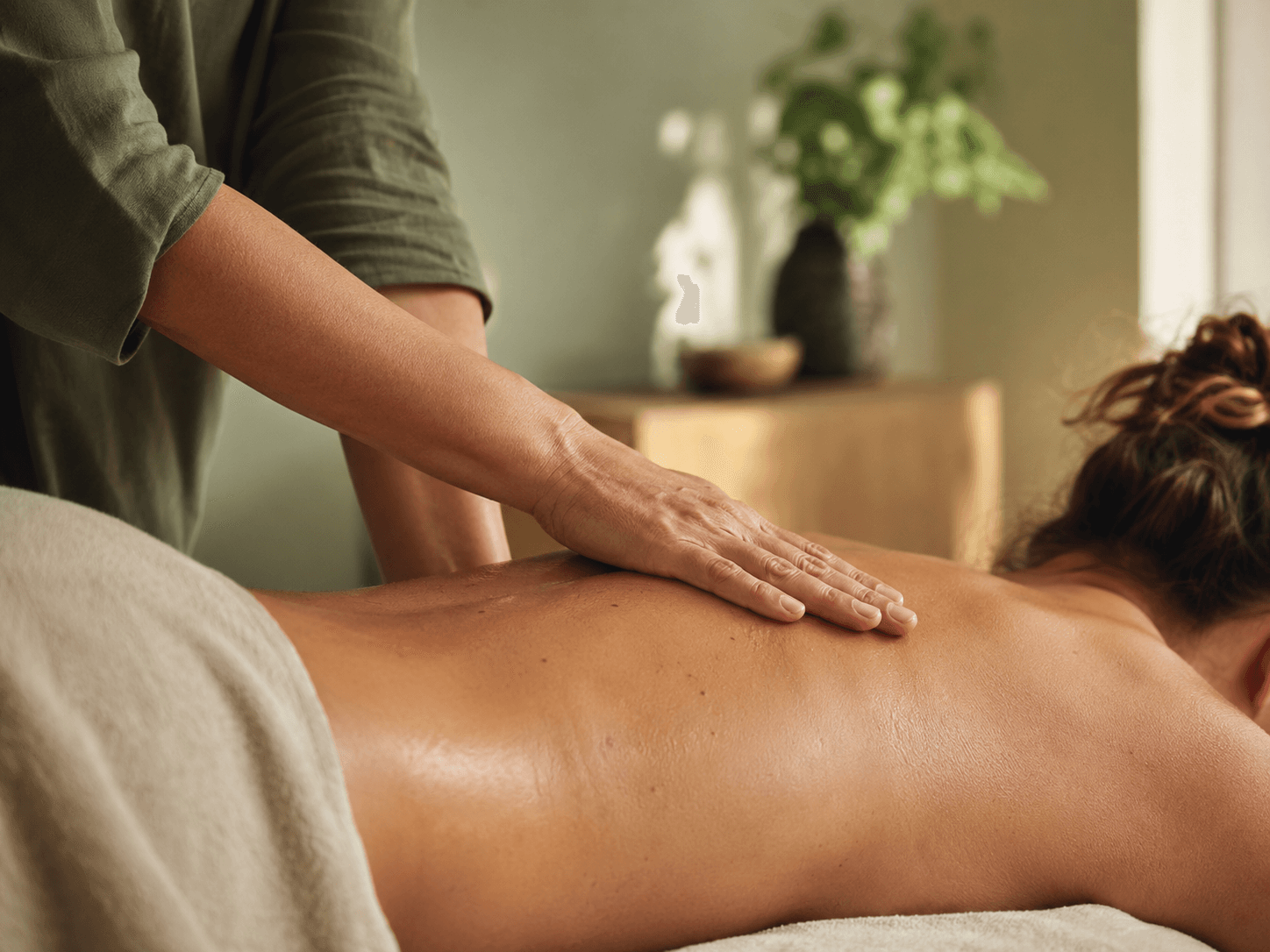 A therapist's hand applying a smooth massage stroke along a client's back